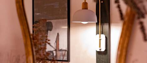 A mirror with a gold frame, a wall-mounted lamp, and a framed picture.