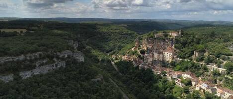 A historic town with a prominent castle, surrounded by lush greenery and a winding road.