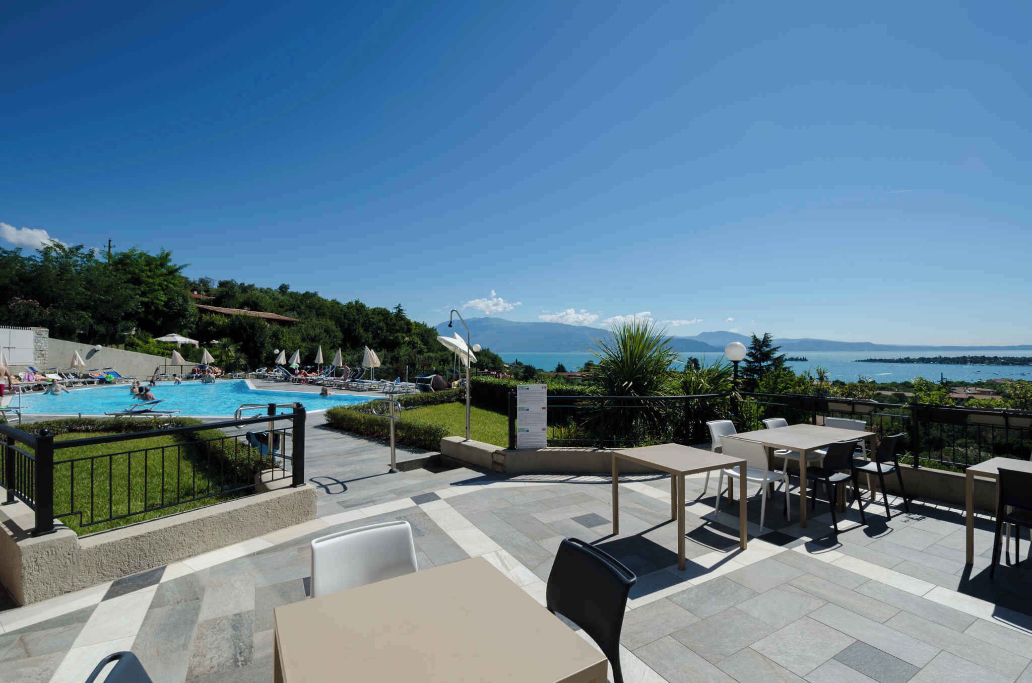 A poolside area with outdoor seating and a view of the sea.