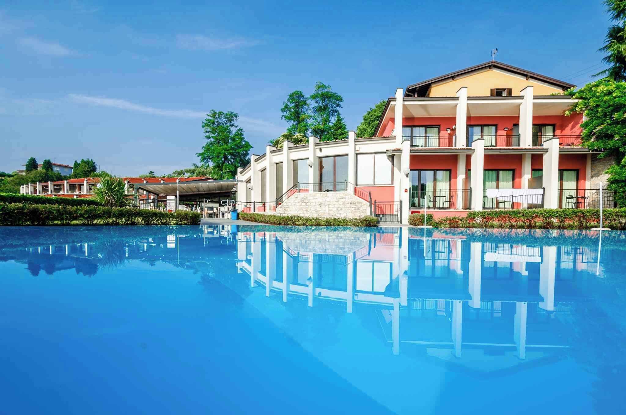 Ein Hotel mit Schwimmbad, überdachtem Außenbereich und einem zweistöckigen Gebäude mit Balkonen.