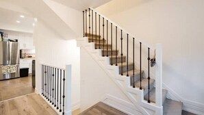 Una escalera moderna con barandilla blanca y escalones de madera que conducen a un segundo piso.