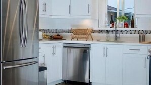 Una cocina moderna con armarios blancos, electrodomésticos de acero inoxidable y un salpicadero de azulejos.