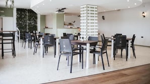 A modern restaurant with a central column, multiple tables, and chairs. - EntreOlivos (Badajoz)