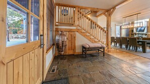 A wooden staircase with a bench, a dining area with chairs, and a stone-tiled floor. - Old Greenwood Cabin 13 (Truckee)