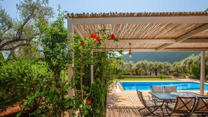Ein überdachter Außenbereich mit Pool, Holzterrasse und Sitzgelegenheiten.