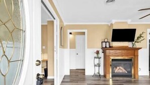 A spacious living room with a fireplace, wooden flooring, and a modern TV. - Ranch near gordyville, sports complex, 13 miles from hospitals (Rantoul)