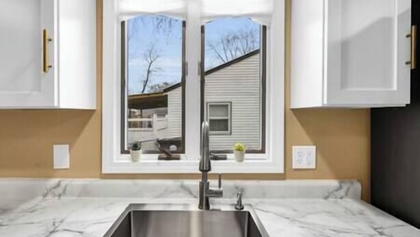A kitchen with a stainless steel sink, white cabinets, and a window with a view of a house. - Ranch near gordyville, sports complex, 13 miles from hospitals (Rantoul)