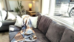 A modern living room with a dark grey sofa, a patterned throw blanket, and a white radiator. - Ranch near gordyville, sports complex, 13 miles from hospitals (Rantoul)