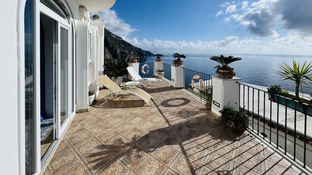 A balcony with a view of the sea, potted plants, and a tiled floor. - YourHome - Assia House Praiano (Praiano)