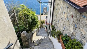 A narrow stone staircase leading to a building with a view of the sea. - YourHome - Assia House Praiano (Praiano)