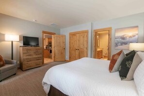 A hotel room with a large bed, a TV, wooden wardrobe, and a view of the mountain landscape. - Old Greenwood Townhome 16A (Truckee)