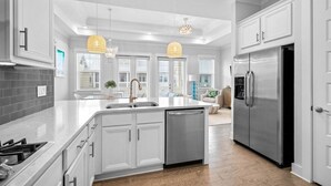 A modern kitchen with white cabinetry, stainless steel appliances, and a central island.
