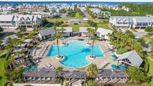 A resort with a central swimming pool, multiple lounge areas, and a view of the ocean.