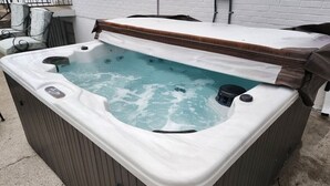 A hot tub with a wooden cover, a white exterior, and a visible water level indicator. - Spacious 3BR Ranch w/ Hot Tub & Yard • Near Kings Island (Mason)