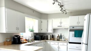 A modern kitchen with white cabinets, a microwave, a stove, and a refrigerator. - Spacious 3BR Ranch w/ Hot Tub & Yard • Near Kings Island (Mason)
