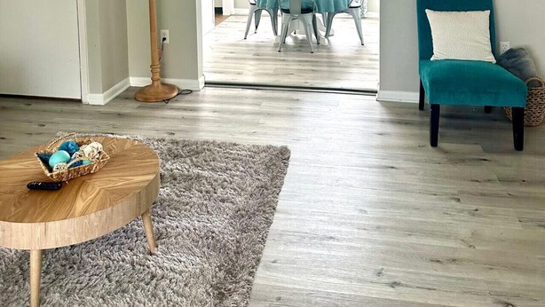 A living room with a round wooden coffee table, a teal armchair, and a grey shaggy rug. - Spacious 3BR Ranch w/ Hot Tub & Yard • Near Kings Island (Mason)