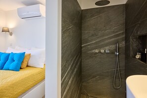 A hotel room with a bed, a shower, and a bathroom.