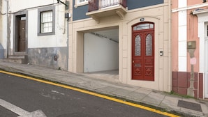Straßenansicht eines Gebäudes mit roter Tür, Garagentor und der Hausnummer 36 an der Fassade.