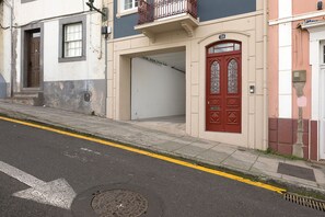 A street view with a building featuring a red door, a garage door, and a visible number '36' on the facade.