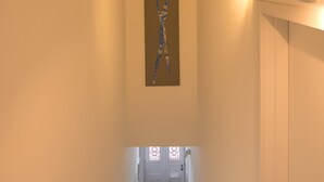Un escalier recouvert d’une moquette rouge, une œuvre d’art accrochée au mur et une porte en bas.