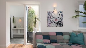 Un salon moderne avec un canapé d’angle, une plante en pot et une œuvre d’art accrochée au mur.