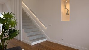 A staircase with a modern design, a potted plant, and a wall-mounted light fixture. - Luna Rossa - Artcooking by Homie (Funchal)