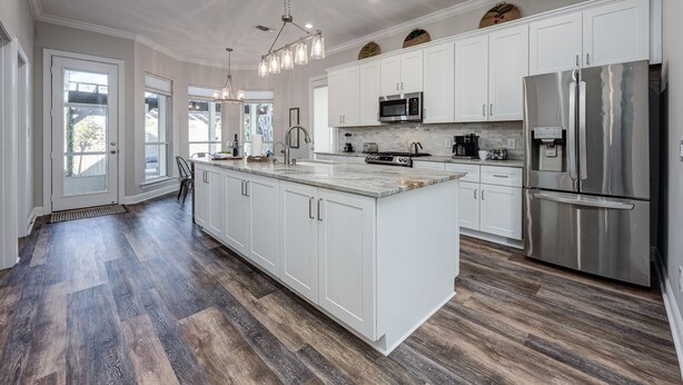 A spacious kitchen with white cabinetry, a stainless steel refrigerator, and a large island. - Lei'd Back * Golf Cart Included & Pet Friendly * Salt Water Vacations (Destin)