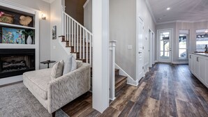 A modern interior with a staircase, a fireplace, and a kitchen area. - Lei'd Back * Golf Cart Included & Pet Friendly * Salt Water Vacations (Destin)