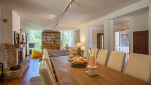 A spacious dining area with a long wooden table, cushioned chairs, and a fireplace. - Camadix, Finca 5StarsHome Mallorca (Costitx)