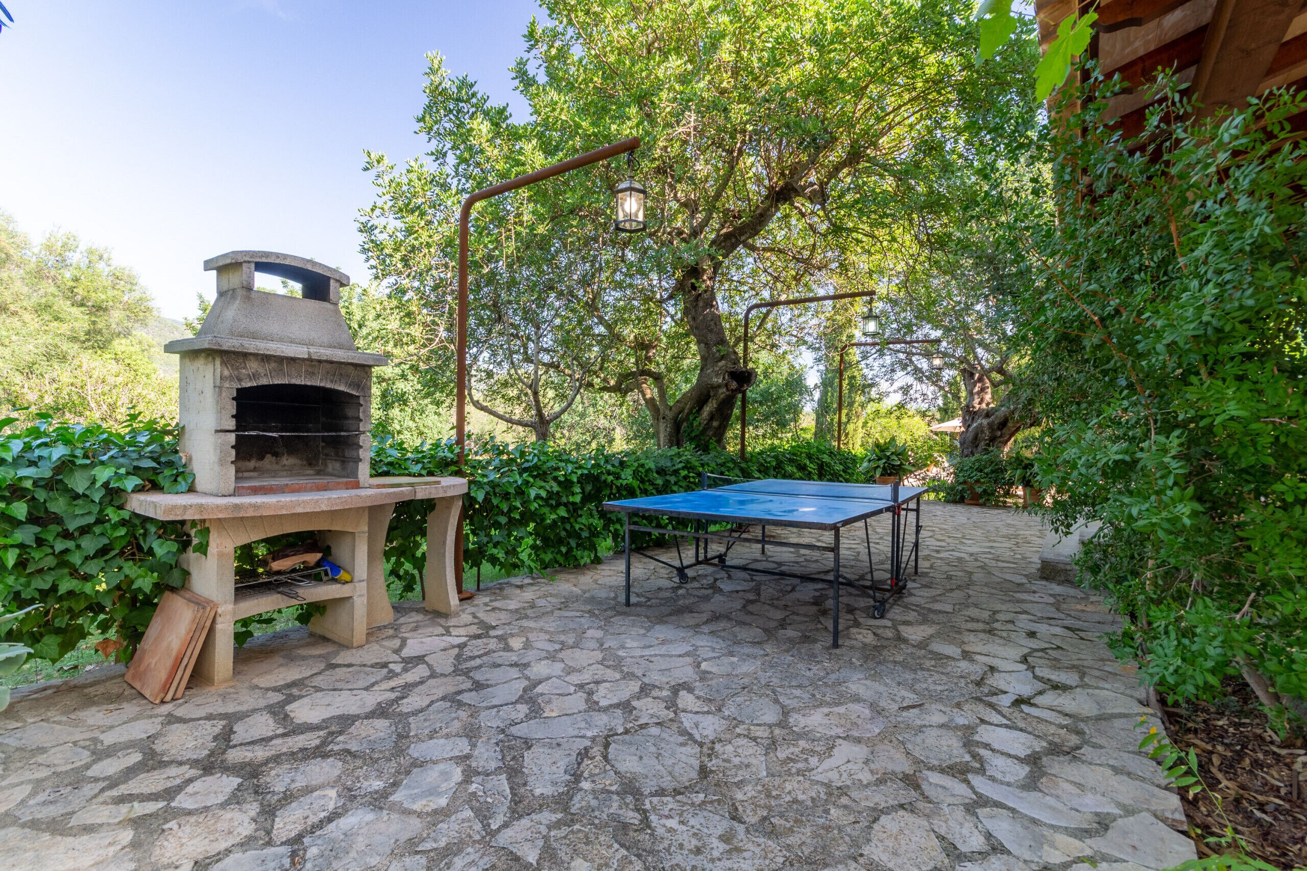 An outdoor patio with a stone floor, a pizza oven, and a ping pong table.