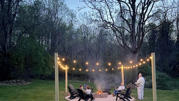 A fire pit area with seating and string lights in a wooded setting. - Peaceful Farmhouse w/ Fire Pit & Updated Comforts (Monroe)