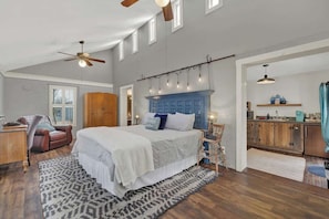 Une chambre à coucher avec un grand lit, un ventilateur de plafond, une armoire en bois, un bureau et une chaise.