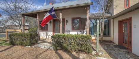 Una casa con porche, una bandera y un camino de piedra.