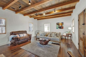 A living room with a brown leather sofa, a wooden coffee table, and a fan.