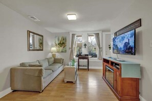 Una sala de estar con un sofá, una mesa de centro, un televisor y un mueble de madera.