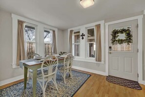 A dining area with a table, chairs, and a patterned rug.