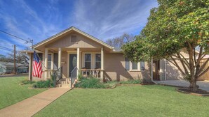 A single-story house with a front porch, a small garden, and an American flag.