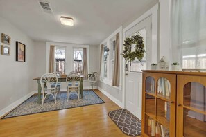 A dining area with a wooden table and chairs, a blue rug, and a wooden cabinet with glass doors.