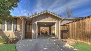 A residential house with a covered entryway, a driveway, and a fenced backyard.