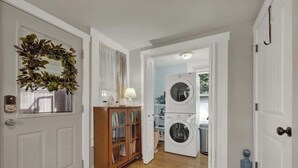A hallway with a wooden cabinet, a washing machine, and a door with a wreath.