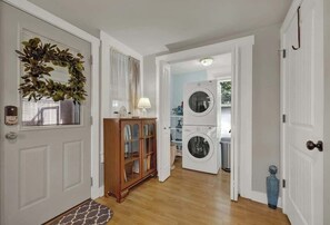 A hallway with a wooden cabinet, a washing machine, and a door with a wreath.