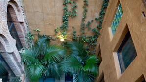 A courtyard with a blue tiled door, brick walls, and green plants. - Hotel Lincoln Lounge (Barcelona)