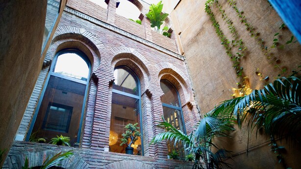 A courtyard with arched brick structures, potted plants, and a view of the sky through windows. - Hotel Lincoln Lounge (Barcelona)