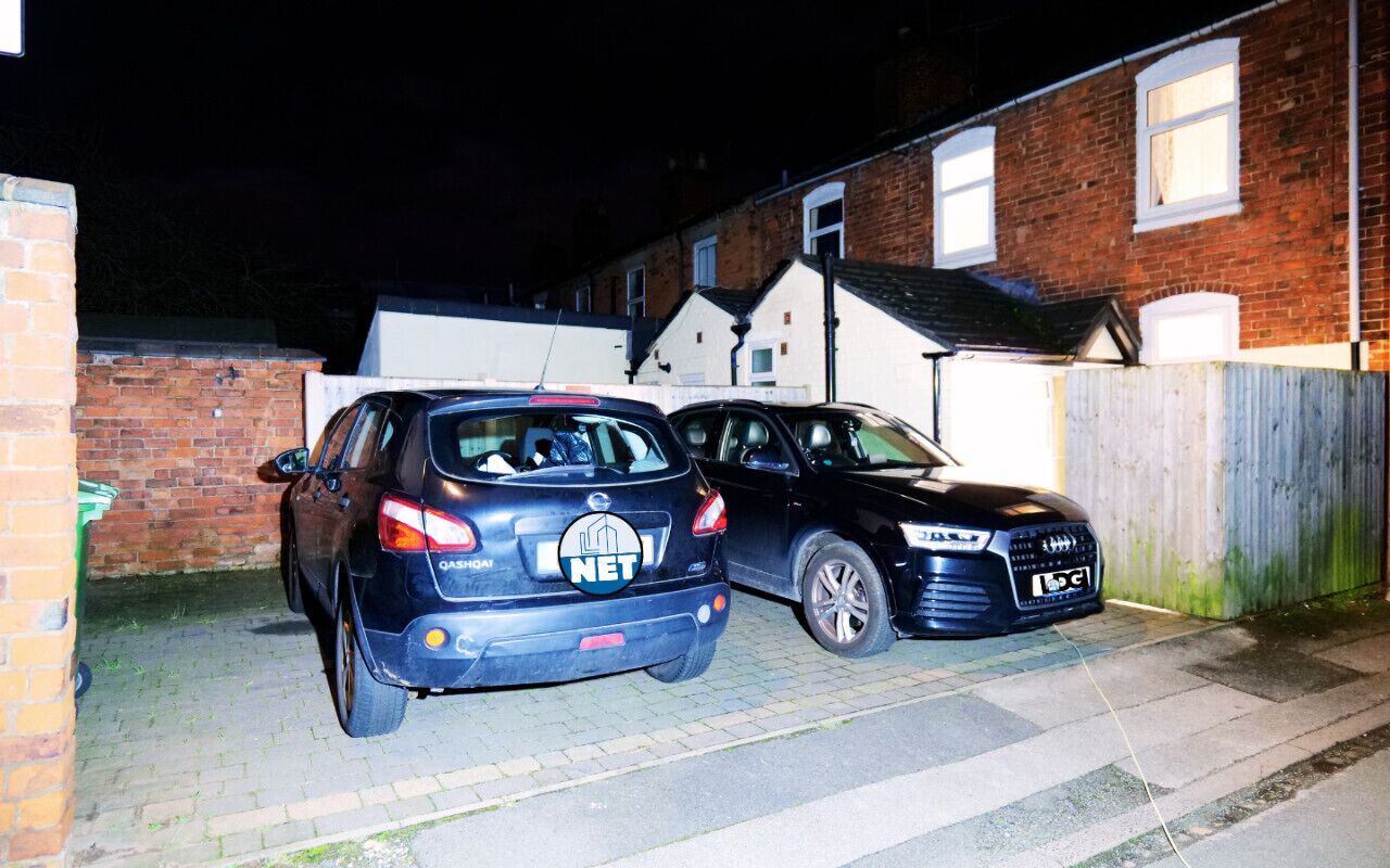 Dos autos estacionados en la entrada de una casa durante la noche.