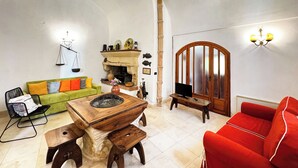 Een woonkamer met een groene bank, een rode bank, een houten salontafel en een open haard.