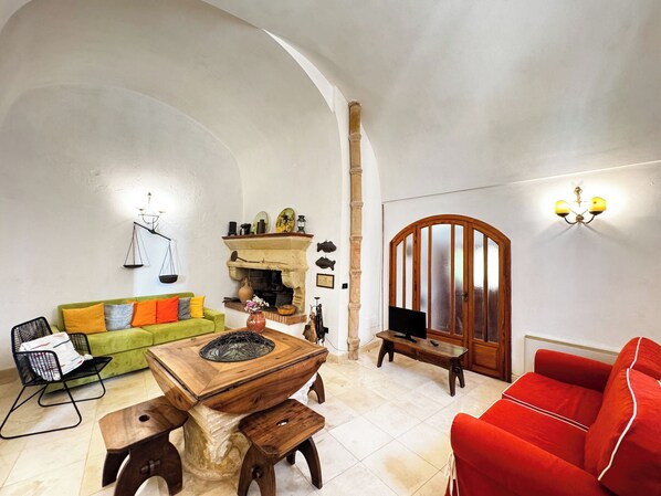 A living room with a green sofa, a red sofa, a wooden coffee table, and a fireplace.