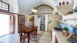 Een keuken met een eethoek, een koelkast, een fornuis en een betegelde achterwand.
