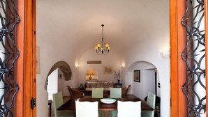 A dining area with a wooden table, green chairs, and a chandelier. - Typical house with a seafront terrace in the center of Otranto - Marea Stays Collection (Otranto)
