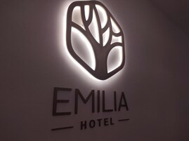 Un logotipo con un diseño de árbol y el texto 'EMILIA HOTEL' debajo.