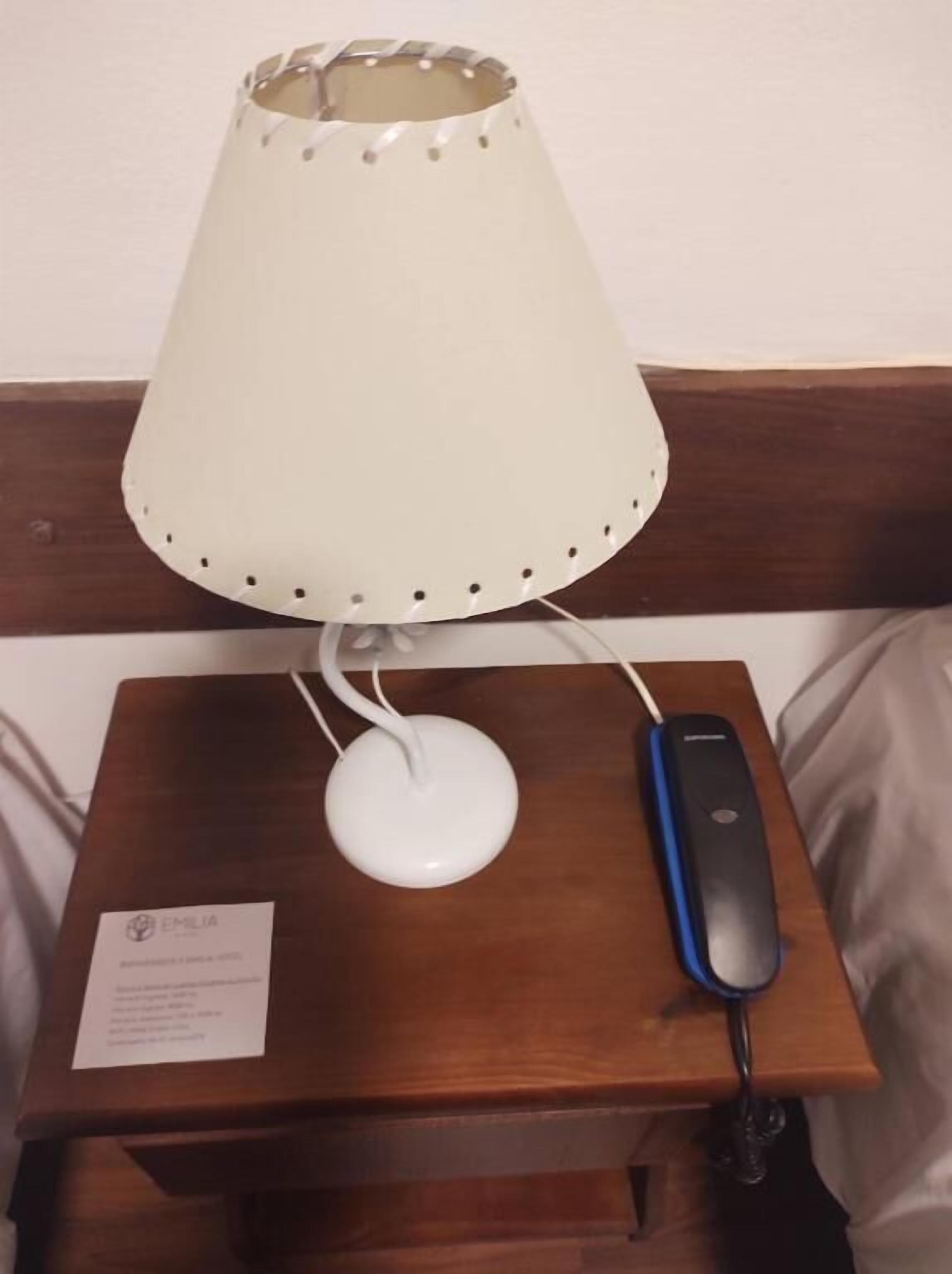 A bedside table with a lamp, a power strip, and a card.